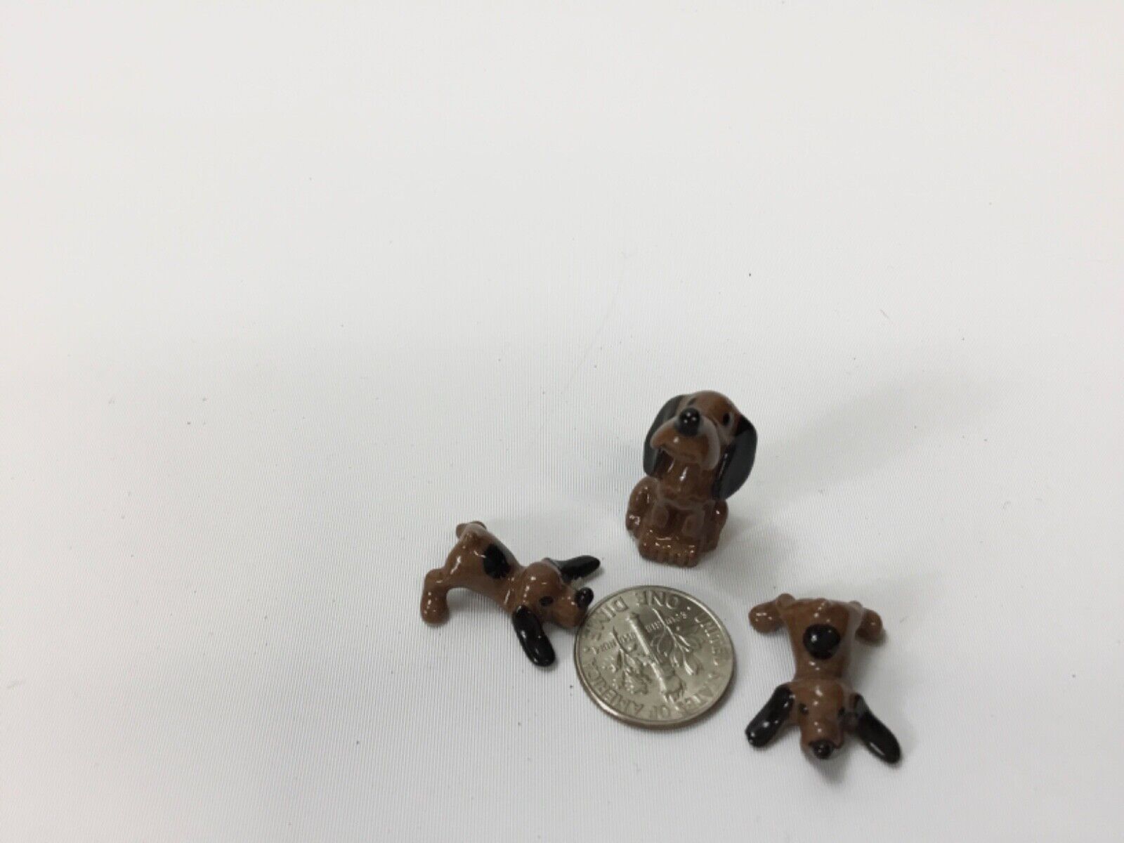3 Miniature Porcelain Dog Figurines. (2) 3/4” Long (1) 1” Tall Hound Dogs